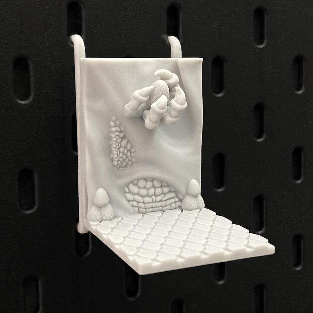 Hand-painted ancient stone dragon claw dice box, mounted on an IKEA SKÅDIS pegboard for TTRPG setup.
